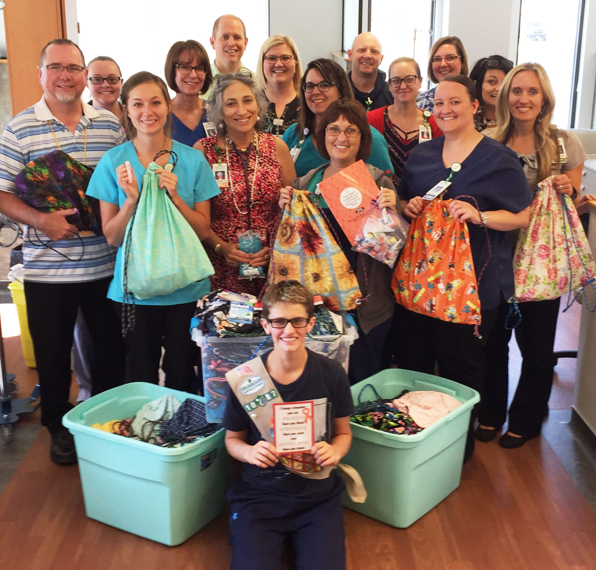 several staff members holding donated chemo bags with a girl scout cadette