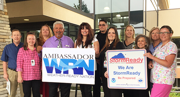 staff members in colorful clothes holding Storm Ready signs